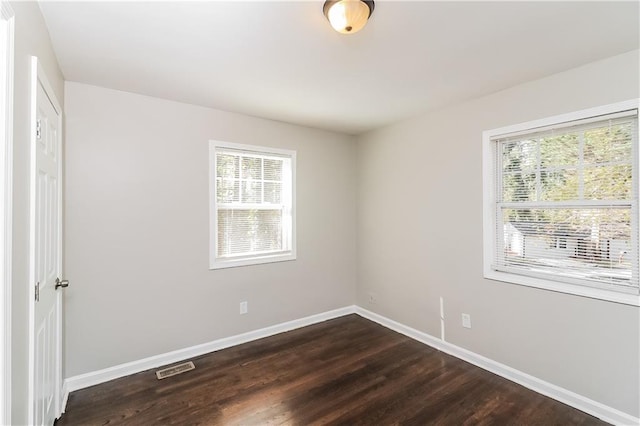 empty room featuring dark wood-type flooring and a wealth of natural light