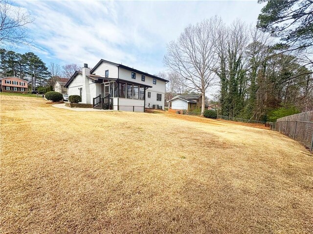 2167 Cedar Dr, Lawrenceville, GA 30043 - exterior space with fence, a chimney, a lawn, and a sunroom