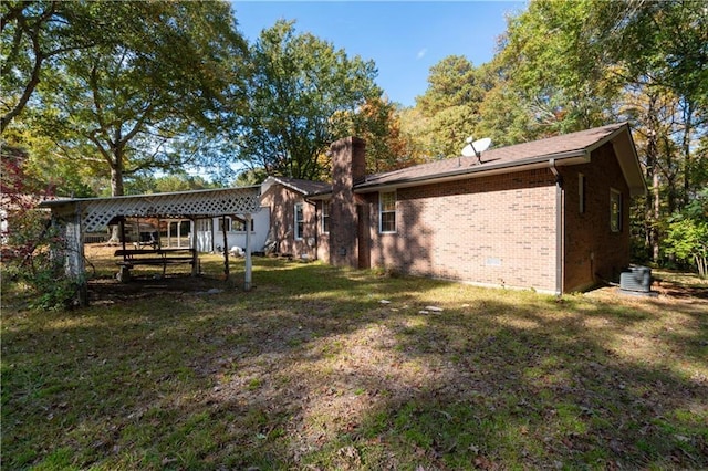 rear view of house featuring a yard and central AC unit