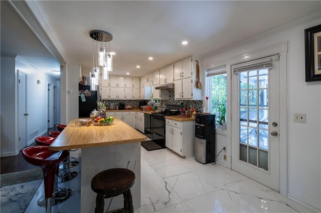 kitchen with pendant lighting, wood counters, tasteful backsplash, white cabinetry, and black appliances