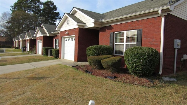 view of side of home with a yard, an attached garage, brick siding, and concrete driveway