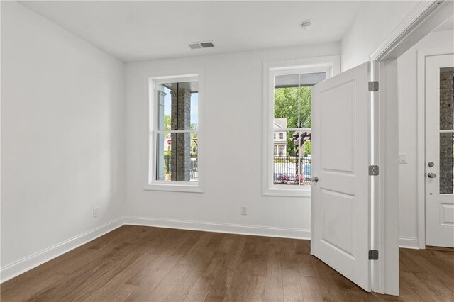 empty room featuring dark wood-style floors, baseboards, and visible vents