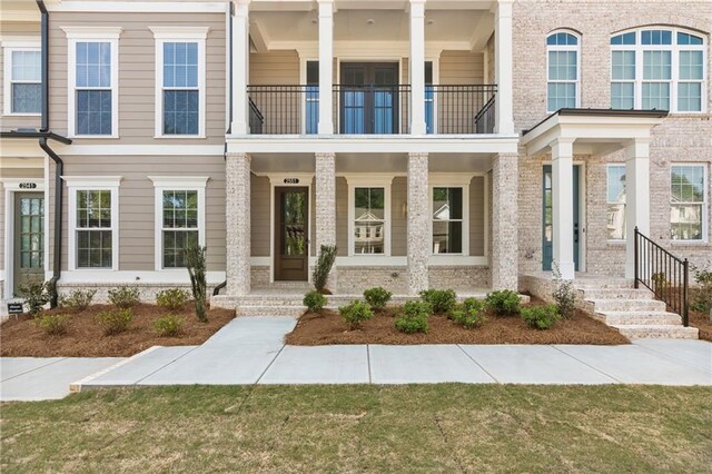 view of front of house with brick siding, a porch, and a balcony