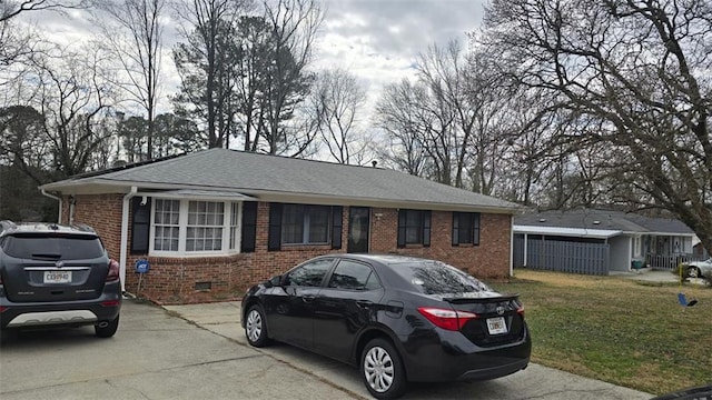 single story home with crawl space, a front yard, brick siding, and a shingled roof