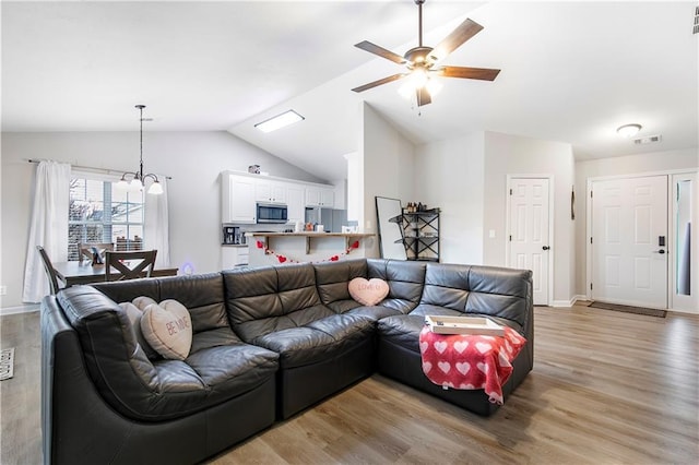 living room featuring visible vents, baseboards, vaulted ceiling, light wood-style floors, and ceiling fan with notable chandelier