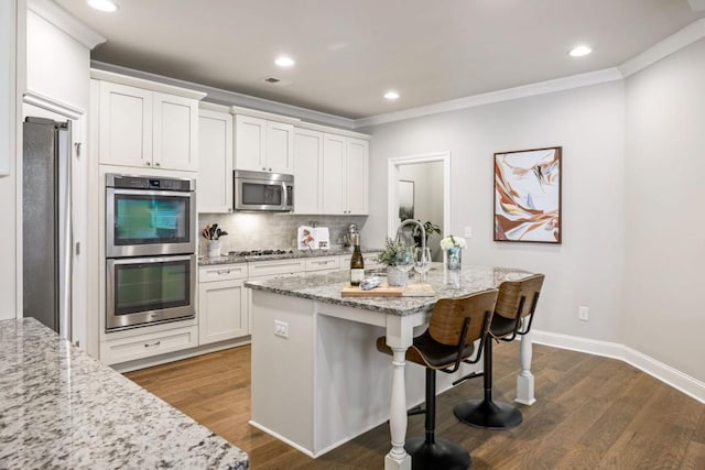 kitchen with crown molding, decorative backsplash, a kitchen breakfast bar, dark wood-style floors, and stainless steel appliances