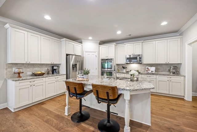 kitchen featuring stainless steel appliances, a kitchen bar, light wood-style floors, and crown molding