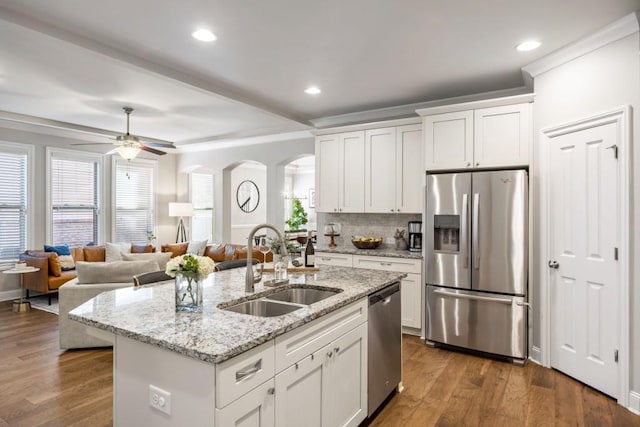 kitchen featuring a sink, stainless steel appliances, arched walkways, and a healthy amount of sunlight