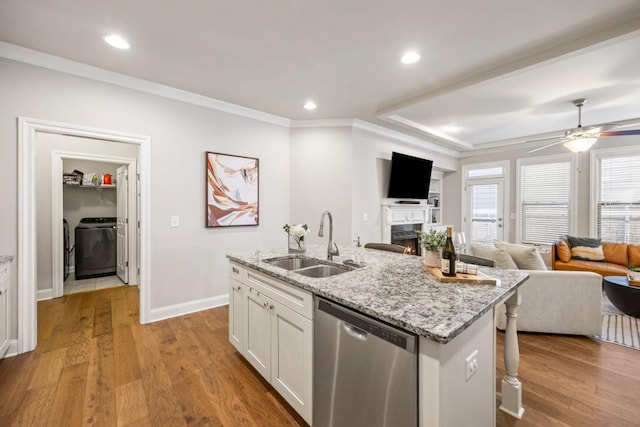 kitchen with open floor plan, stainless steel dishwasher, wood finished floors, washer / clothes dryer, and a sink