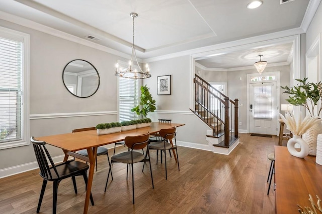 dining space with wood finished floors, baseboards, stairs, a raised ceiling, and a notable chandelier