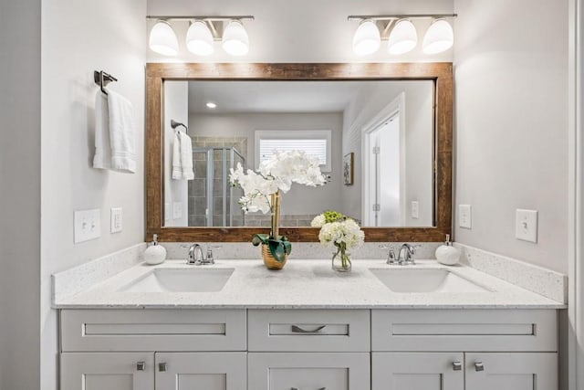 bathroom with double vanity, a shower stall, and a sink