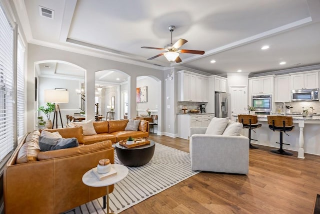 living area featuring visible vents, a raised ceiling, a healthy amount of sunlight, and wood finished floors