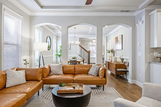 living room featuring crown molding, wood finished floors, baseboards, and a raised ceiling