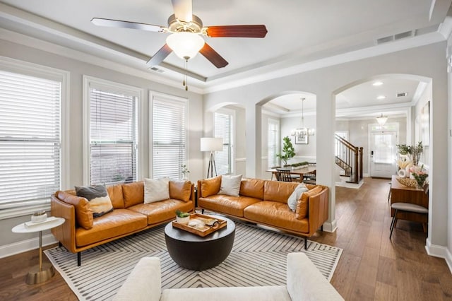 living room with visible vents, a tray ceiling, wood finished floors, arched walkways, and crown molding