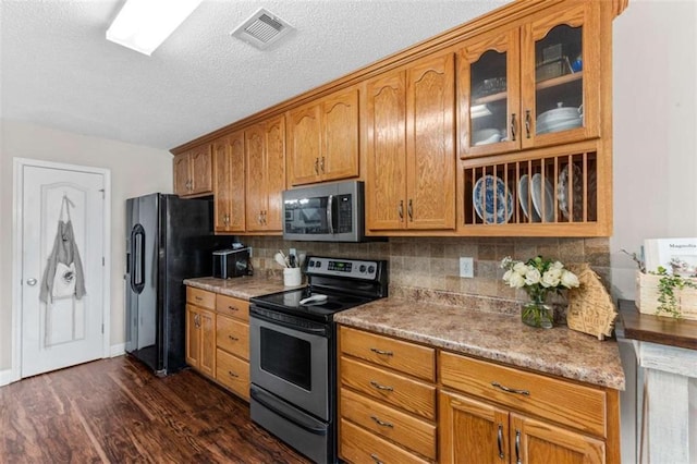 102 Blackstone Ct, Kathleen, GA 31047 - kitchen featuring appliances with stainless steel finishes, glass insert cabinets, backsplash, a textured ceiling, and dark wood-style floors