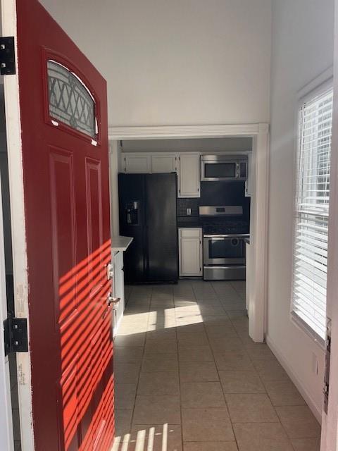 kitchen featuring appliances with stainless steel finishes, tile patterned flooring, and white cabinets