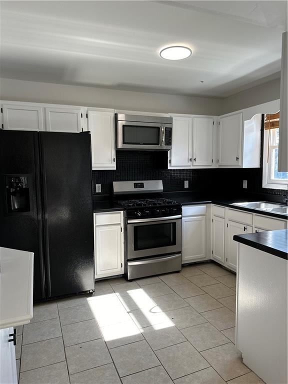 kitchen featuring appliances with stainless steel finishes, white cabinetry, sink, backsplash, and light tile patterned floors