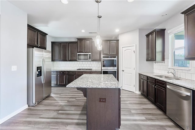 kitchen featuring dark brown cabinetry, a sink, light wood-style floors, appliances with stainless steel finishes, and a center island