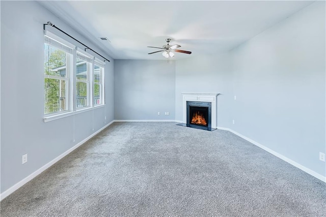 unfurnished living room with baseboards, visible vents, ceiling fan, carpet, and a fireplace