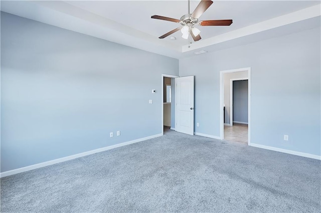 unfurnished bedroom featuring carpet, baseboards, ceiling fan, and a tray ceiling