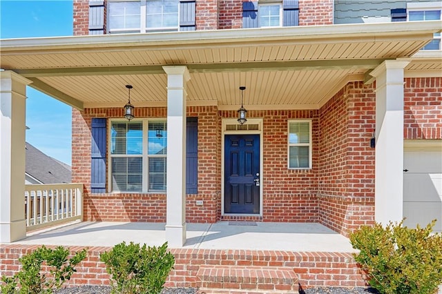 view of exterior entry featuring a porch and brick siding