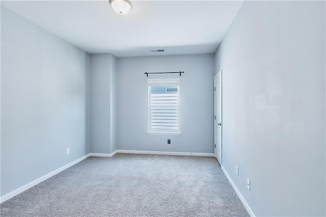 unfurnished room with carpet, visible vents, and baseboards