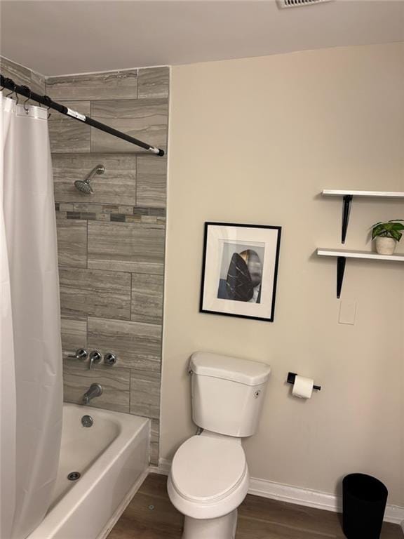 bathroom featuring hardwood / wood-style flooring, shower / bath combination with curtain, and toilet