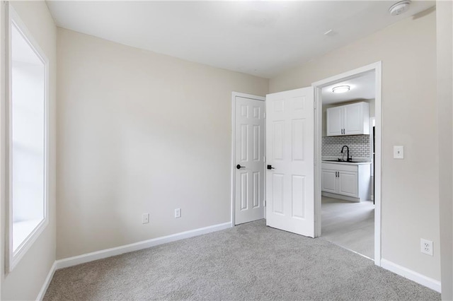 unfurnished bedroom featuring sink and light carpet