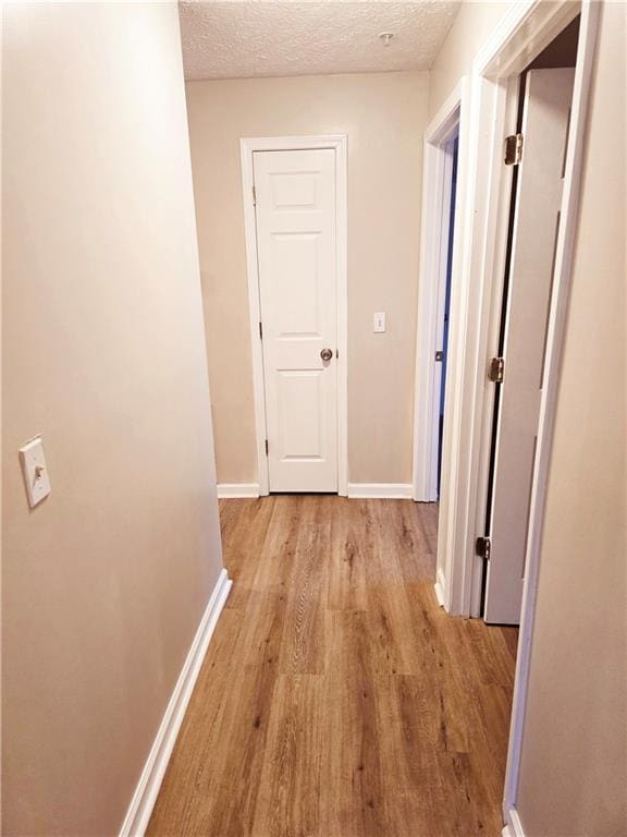 hall featuring light wood-type flooring and a textured ceiling