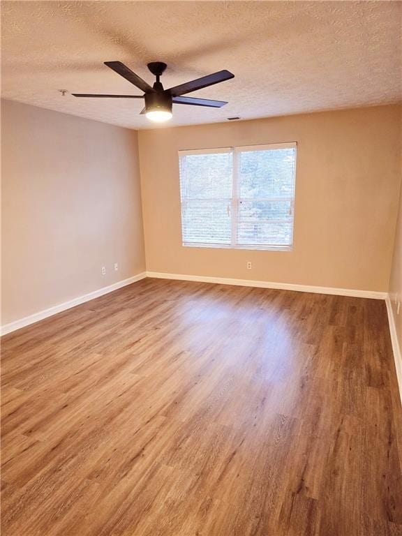 spare room featuring ceiling fan, wood-type flooring, and a textured ceiling