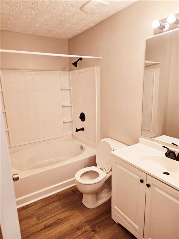 full bathroom featuring shower / bath combination, hardwood / wood-style floors, vanity, a textured ceiling, and toilet