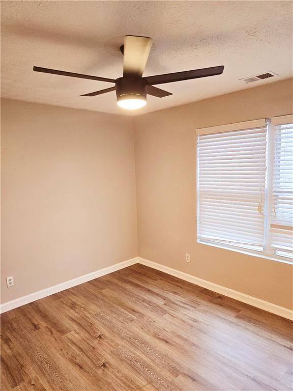 unfurnished room featuring ceiling fan, hardwood / wood-style flooring, and a textured ceiling