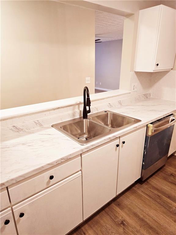 kitchen with sink, dishwasher, dark hardwood / wood-style floors, a textured ceiling, and white cabinets