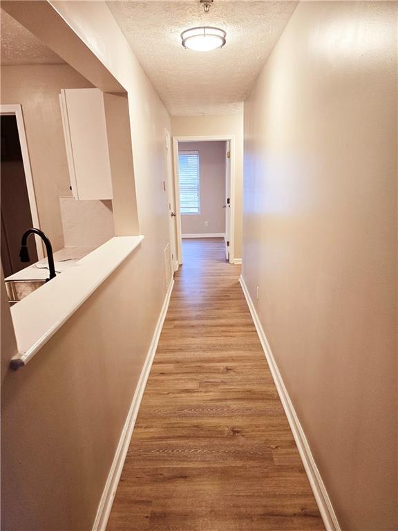 hallway with light hardwood / wood-style flooring and a textured ceiling