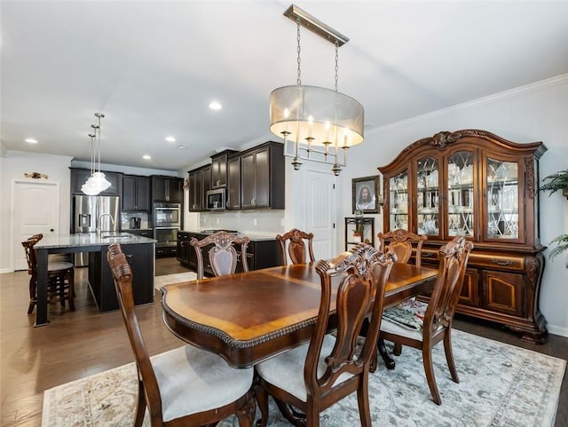 dining area with crown molding, sink, and dark hardwood / wood-style flooring