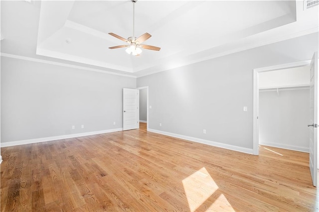 unfurnished bedroom featuring ceiling fan, ornamental molding, a raised ceiling, and light wood-type flooring