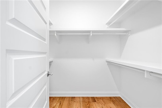 walk in closet with light hardwood / wood-style floors