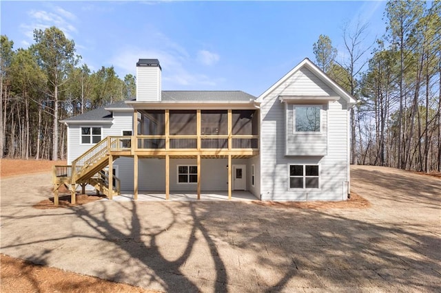 rear view of house with a deck, a patio area, and a sunroom