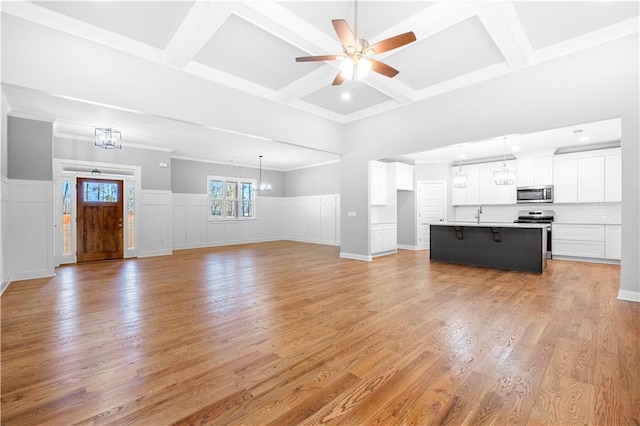 unfurnished living room with coffered ceiling, ceiling fan with notable chandelier, light wood-type flooring, beam ceiling, and sink