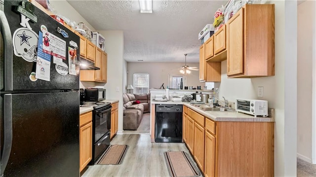 kitchen with a textured ceiling, a sink, open floor plan, light countertops, and black appliances