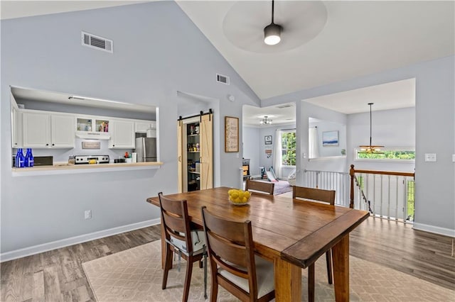 115 Donna Dr, Dawsonville, GA 30534 - dining room with wood finished floors, a ceiling fan, a barn door, and high vaulted ceiling