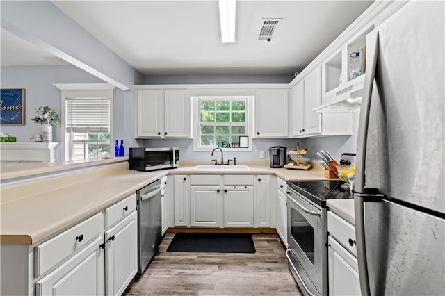 115 Donna Dr, Dawsonville, GA 30534 - kitchen with appliances with stainless steel finishes, wood finished floors, white cabinets, light countertops, and under cabinet range hood