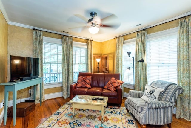 living area with wood-type flooring, ceiling fan, and crown molding