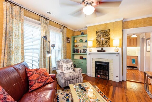 living room featuring ceiling fan, ornamental molding, sink, a fireplace, and hardwood / wood-style floors