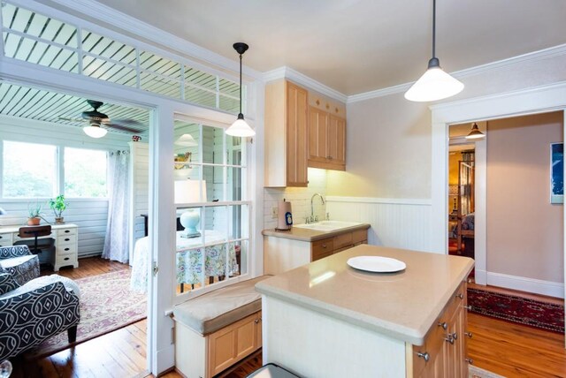 kitchen with ornamental molding, a kitchen island, light brown cabinetry, and light hardwood / wood-style flooring