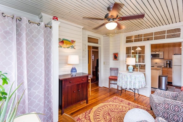 living room featuring light wood-type flooring, wood walls, ceiling fan, and wooden ceiling