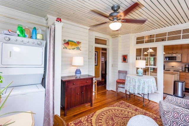 interior space featuring stacked washer and clothes dryer, wood walls, wooden ceiling, ceiling fan, and hardwood / wood-style floors