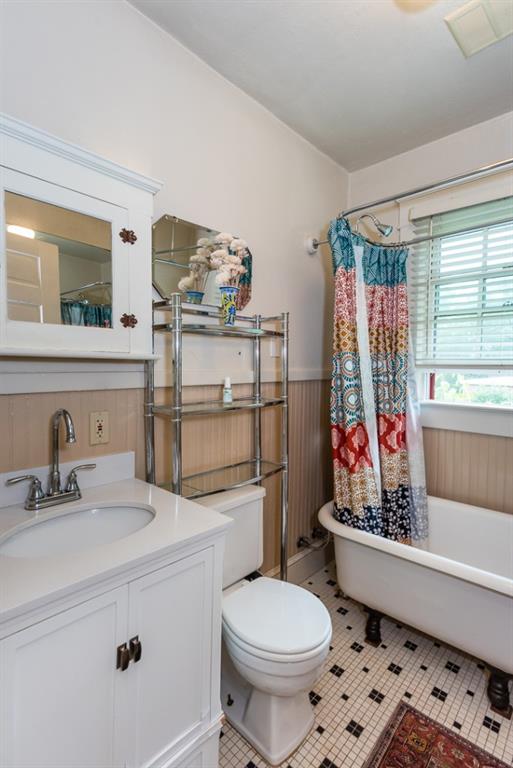 bathroom with tile patterned floors, wood walls, vanity, and toilet