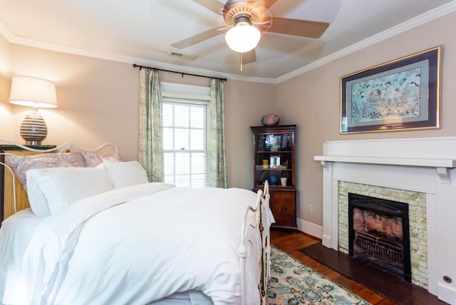 bedroom with crown molding, a fireplace, dark hardwood / wood-style floors, and ceiling fan