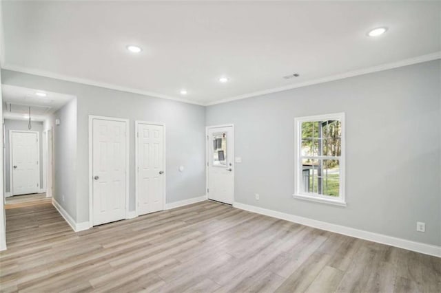 spare room with crown molding and light wood-type flooring